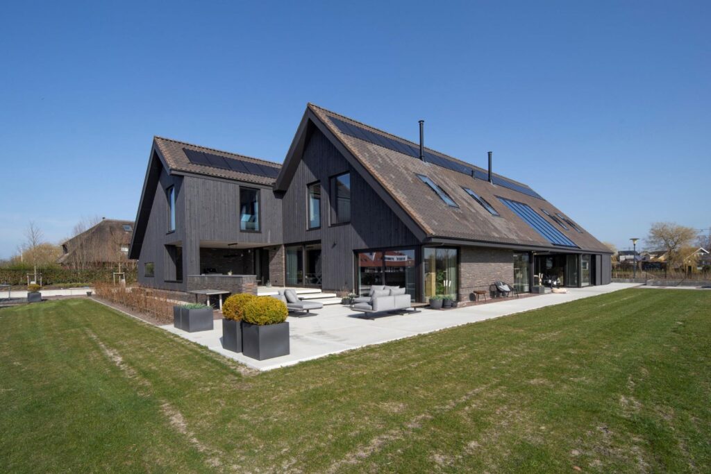 Donkergrijze villa van buitenaf met gras op voorgrond en blauwe lucht